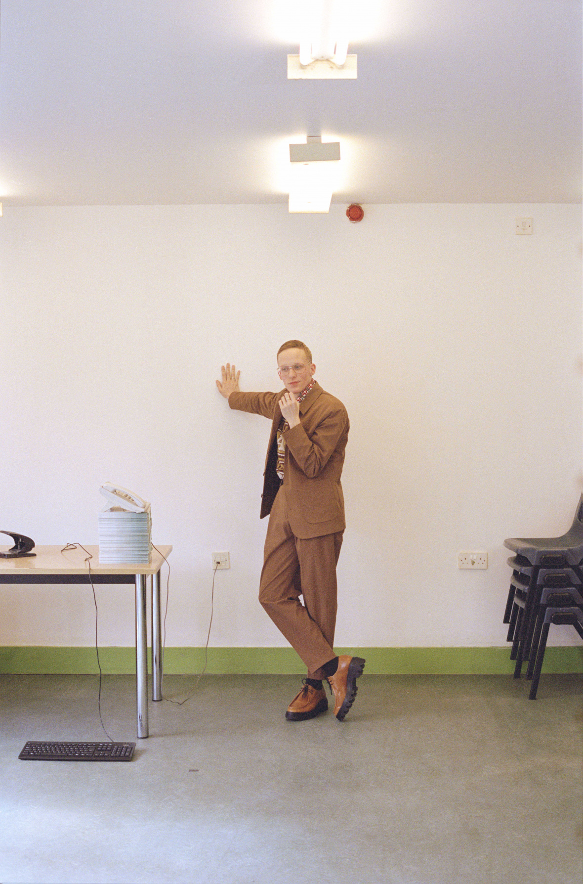 Sweater by ADAM JONES, Vintage shirt from COSTUME STUDIO, Suit by UNIQLO, Belt and tie — Stylist’s own, Socks by FALKE, Vintage shoes by PRADA, Glasses by LINDA FARROW